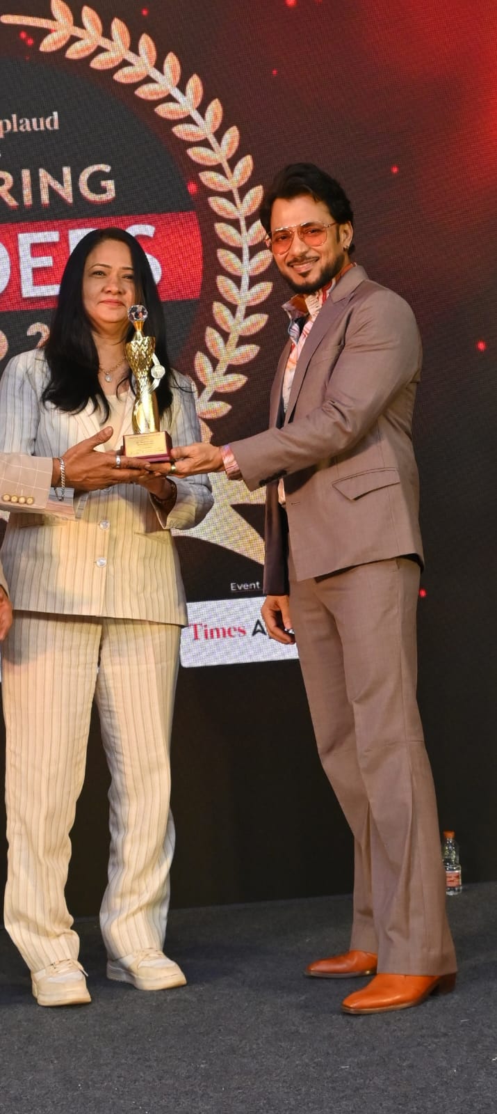 Dr. Reshma Jain receiving an award on stage from Shark Tank India judge Anupam Mittal